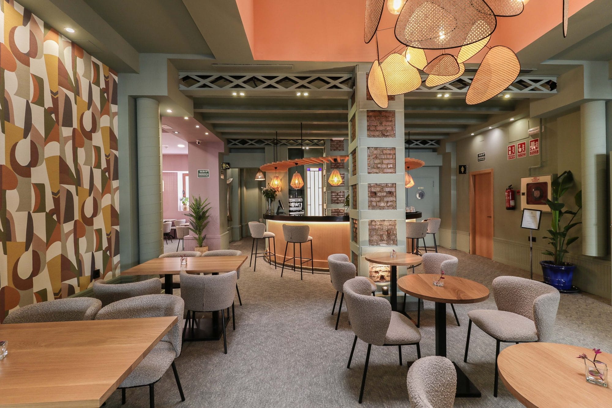 Comedor de restaurante con mesas redondas, sillas tapizadas de diseño, iluminación integrada en el techo y un ambiente cálido y sofisticado.