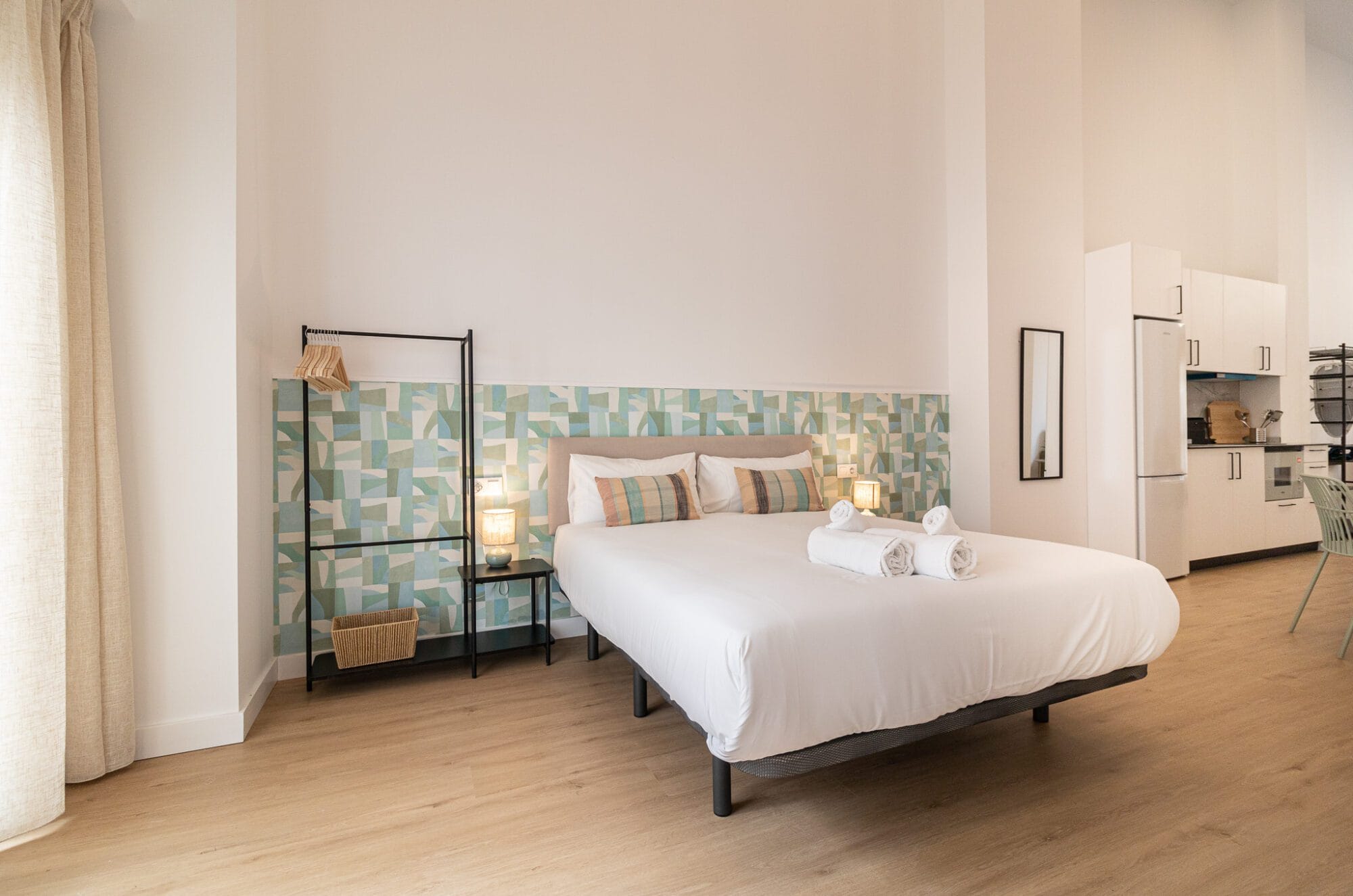 Distribución y reforma de un apartamento alargado con cocina integrada de muebles blancos y un dormitorio al fondo separado visualmente.